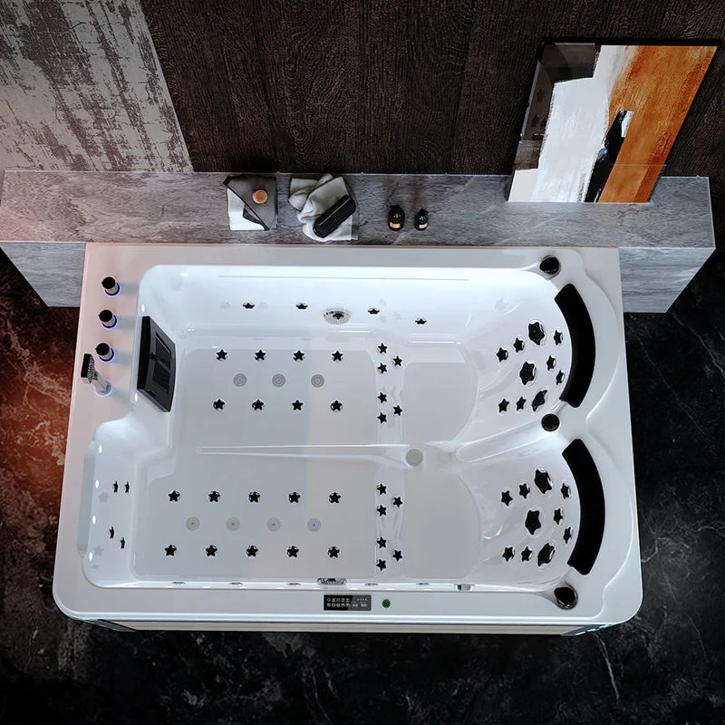 White rectangular hot tub with star-shaped jets, viewed from above in a rustic bathroom setting with textured walls.