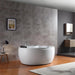 Modern bathroom with white freestanding tub, gray stone tiles, wooden floor, and minimalist decor including a table lamp and landscape artwork.