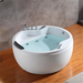 Modern round white jacuzzi tub with blue water, mounted on wooden floor with marble wall tiles and chrome fixtures.