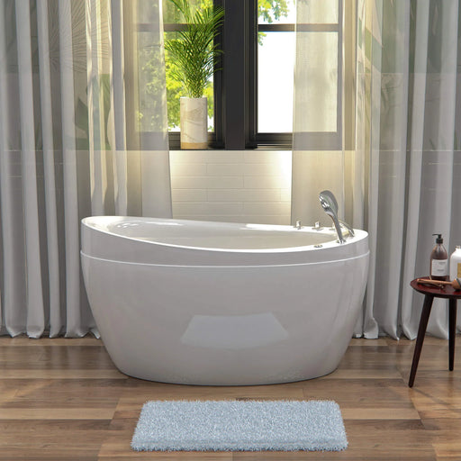 Modern white freestanding bathtub near curtained window, with soft blue bath mat, wooden floor, and potted plant.