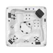 White hot tub with multiple jet nozzles, contoured seating areas, and a black control panel in the corner.