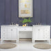 Elegant white bathroom vanity with double sinks, marble countertop, candles, green plant, and framed abstract art on dark blue wall.