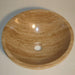 Polished stone vessel sink in warm beige with natural wood-like grain patterns, featuring a central drainage hole.