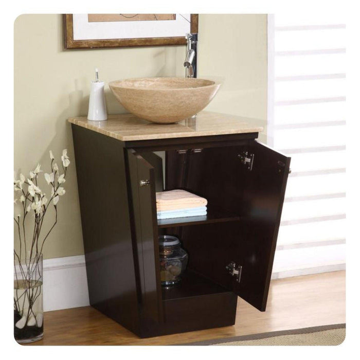Dark wood bathroom vanity with stone vessel sink, open cabinet revealing folded towels and decorative vase of white branches.