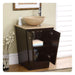 Dark wood bathroom vanity with stone vessel sink, open cabinet revealing folded towels and decorative vase with white branches nearby.