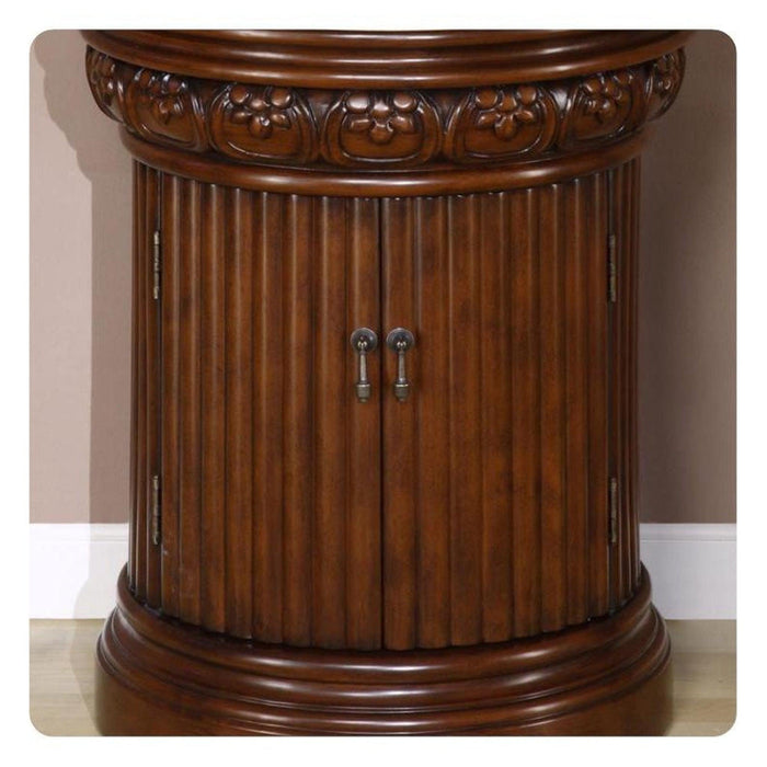 Ornate dark wood column-style cabinet with carved floral top and vertical ribbed sides, double doors with metal knobs