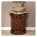 Ornate wooden bathroom vanity with carved column base, marble top, and round stone vessel sink with chrome faucet.