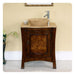 Dark wood bathroom vanity with travertine vessel sink and modern chrome faucet, against cream-colored wall