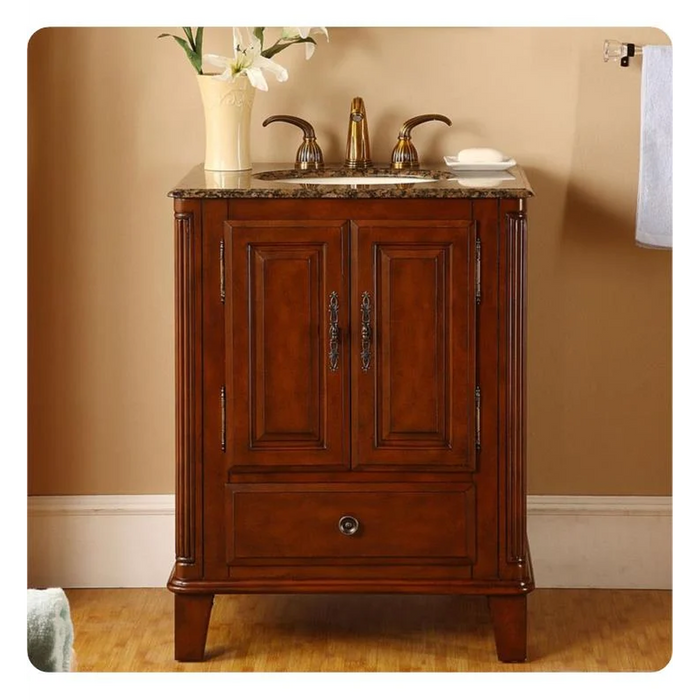 Rich cherry wood bathroom vanity with granite top, white faucet, and decorative white lily in a vase.