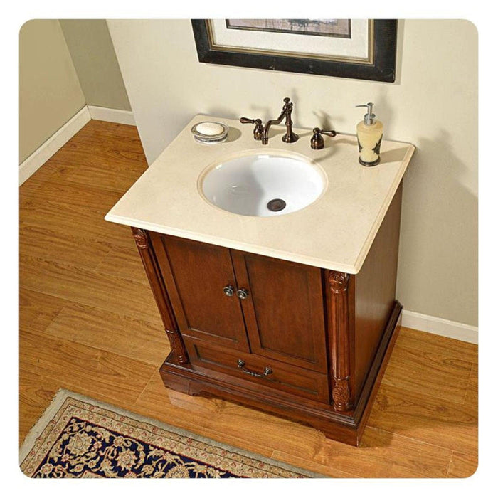 Traditional wooden bathroom vanity with white marble top, oval sink, bronze faucet, and decorative Persian rug on hardwood floor.