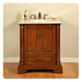 Traditional wooden bathroom vanity with marble top, decorative columns, and bronze fixtures and soap dispenser.