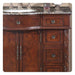 Rich mahogany bathroom vanity with ornate hardware, marble countertop, and decorative carved details on cabinet doors and drawers.