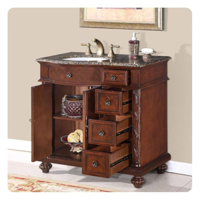 Antique wooden bathroom vanity with marble top, open drawers revealing ornate storage, brass faucet, and decorative accessories.