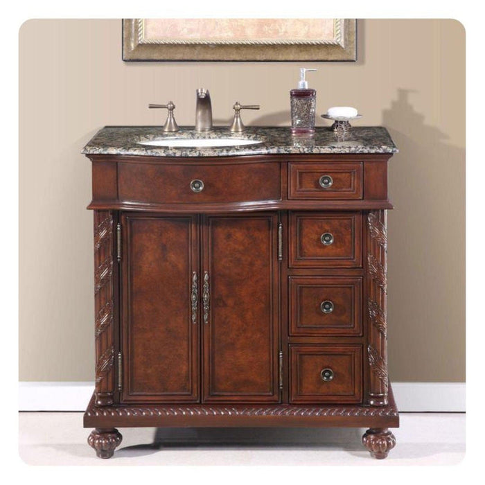Rich mahogany bathroom vanity with granite top, ornate carved details, and two cabinet doors with three side drawers.