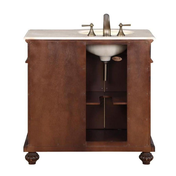 Wooden bathroom vanity with marble top, antique bronze faucet, and open storage shelf, mounted on ornate carved feet.