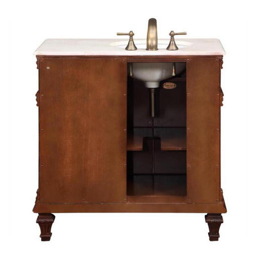 Wooden bathroom vanity with white marble top, brushed nickel faucet, and open storage shelves on ornate carved legs.