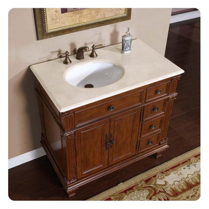 Antique-style wooden bathroom vanity with white marble top, bronze faucet, and decorative cabinet with drawers and ornate hardware.
