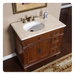Antique-style wooden bathroom vanity with white marble top, bronze faucet, and decorative cabinet with drawers and ornate hardware.