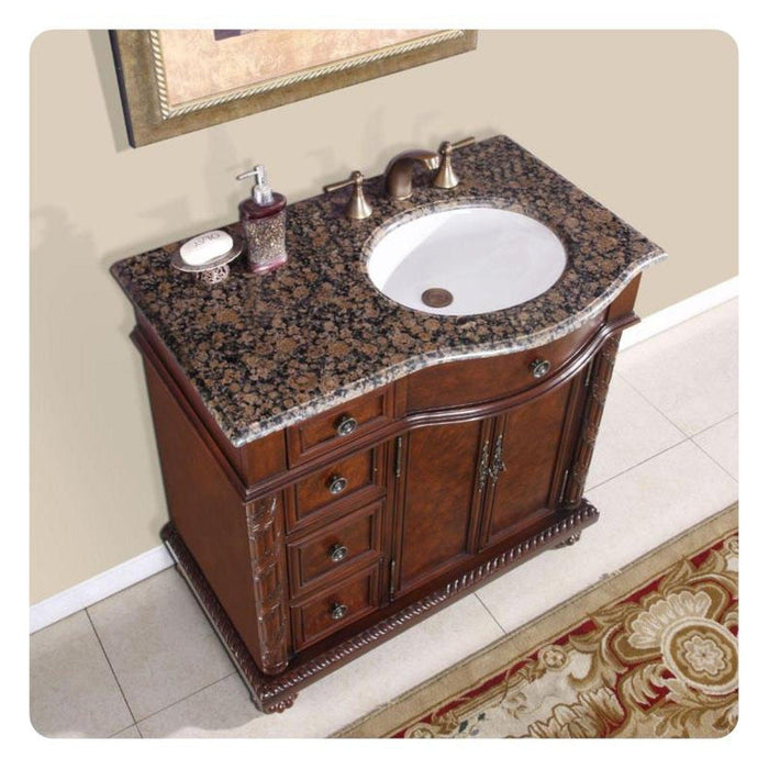 Elegant wooden bathroom vanity with granite top, white sink, and ornate soap dispensers, featuring rich brown woodwork and decorative details.