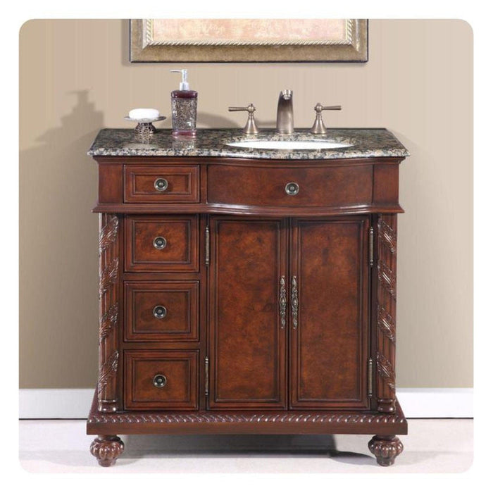 Ornate wooden bathroom vanity with marble top, three drawers, center cabinet doors, and brushed nickel faucet