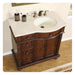 Elegant wooden bathroom vanity with white stone top, three drawers, curved cabinet doors, and bronze faucet fixtures.
