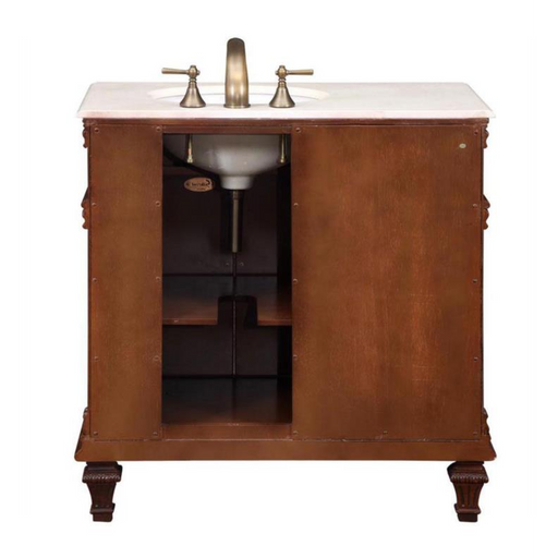 Wooden bathroom vanity with white marble top, antique brass faucet, and carved legs, featuring open storage compartment.