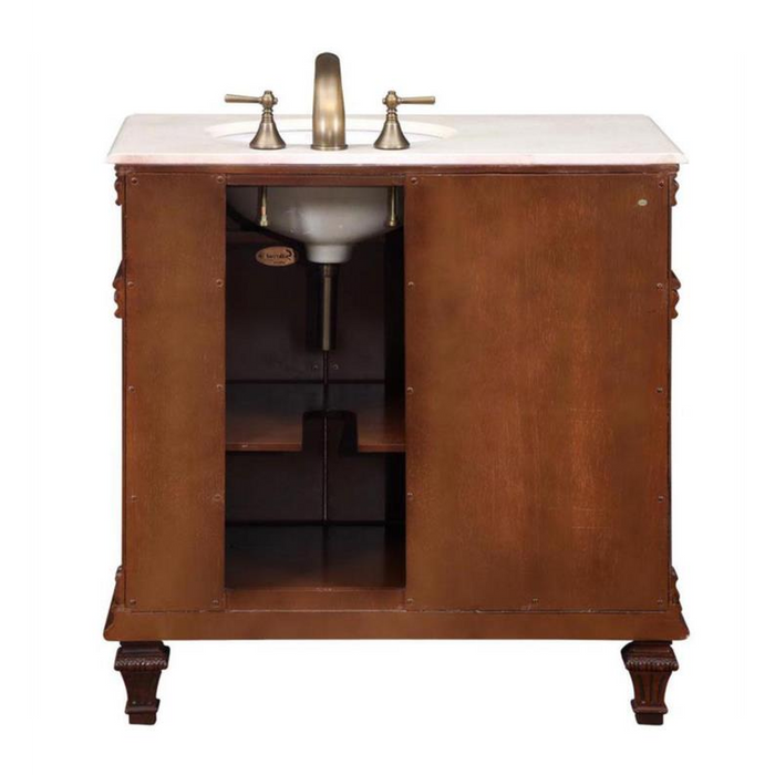 Wooden bathroom vanity with white marble top, antique brass faucet, and carved legs, featuring open storage compartment.
