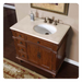 Antique-style wooden bathroom vanity with white marble top, oval sink, and ornate bronze faucet fixtures.