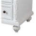 White wooden dresser corner with ornate carved details, dark round knob, and decorative bun foot