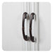 Two dark wooden curved door handles on a white paneled surface, with decorative twisted details at their center.