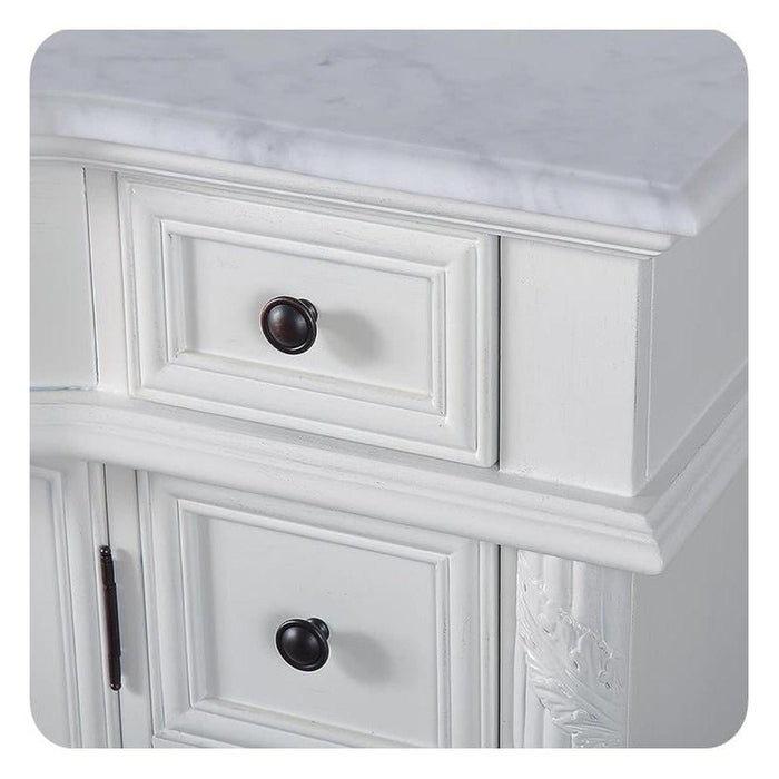 White wooden cabinet with raised panel drawers and black round knobs, marble-like top surface.