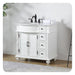 White bathroom vanity with black faucet, three drawers, double cabinet doors, and decorative turned legs.
