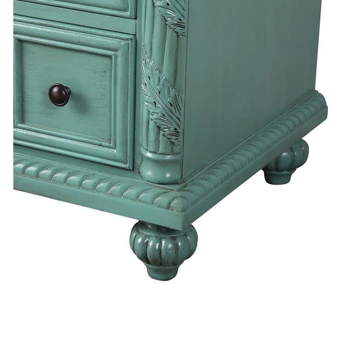 Vintage sage green dresser with ornate carved details, decorative drawer pull, and curved bun feet.