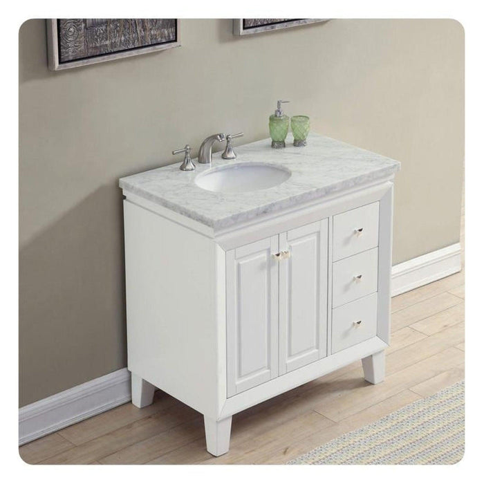White bathroom vanity with marble countertop, undermount sink, and chrome faucet, with green soap dispenser and tumbler.