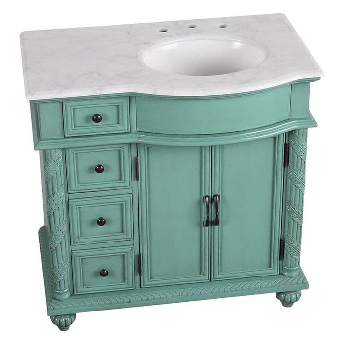 Vintage-style teal bathroom vanity with white marble top, three drawers, and double cabinet doors with ornate details.