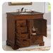Classic wooden bathroom vanity with marble top, bronze fixtures, and multiple drawers open to reveal interior storage.