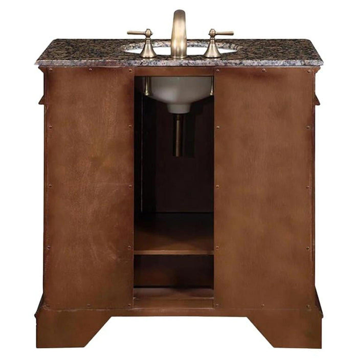 Wooden bathroom vanity with marble countertop and brushed nickel faucet, featuring rich brown cabinetry and open storage space.