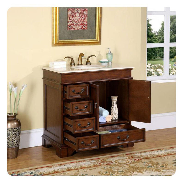 Rich wood bathroom vanity with white marble top, open drawers revealing storage, decorative faucet, and window overlooking green garden