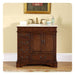 Dark wood bathroom vanity with white marble top, brass faucet, and decorative framed artwork above