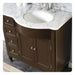 Dark wood bathroom vanity with white marble countertop and oval undermount sink, featuring drawers and cabinet doors with silver hardware