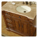 Antique-style wooden bathroom vanity with travertine countertop, white sink, and ornate carved details on cabinet