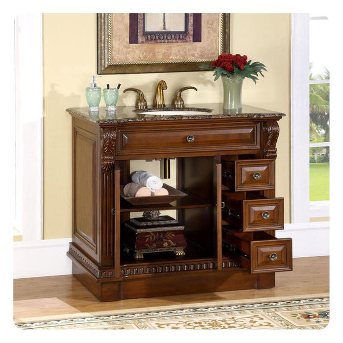 Elegant wood bathroom vanity with marble top, curved drawers, rolled towels, and red flowers in a green vase.