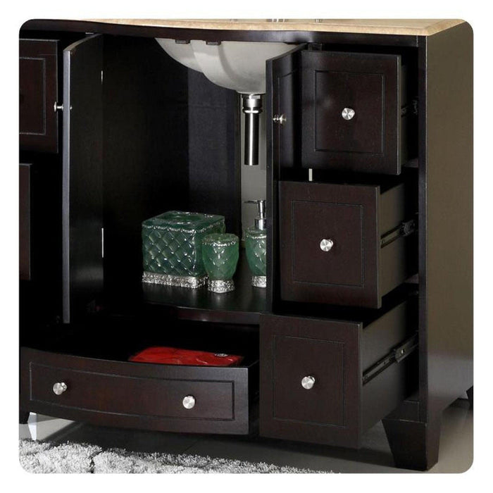 Dark wood bathroom vanity with open cabinet, green decorative glass containers, white sink, and multiple drawers with chrome knobs.