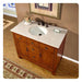Wooden bathroom vanity with white marble top, oval sink, bronze faucet, and small floral arrangement