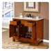 Wooden bathroom vanity with white marble top, open drawers, cabinet doors, and decorative floral arrangement near sink