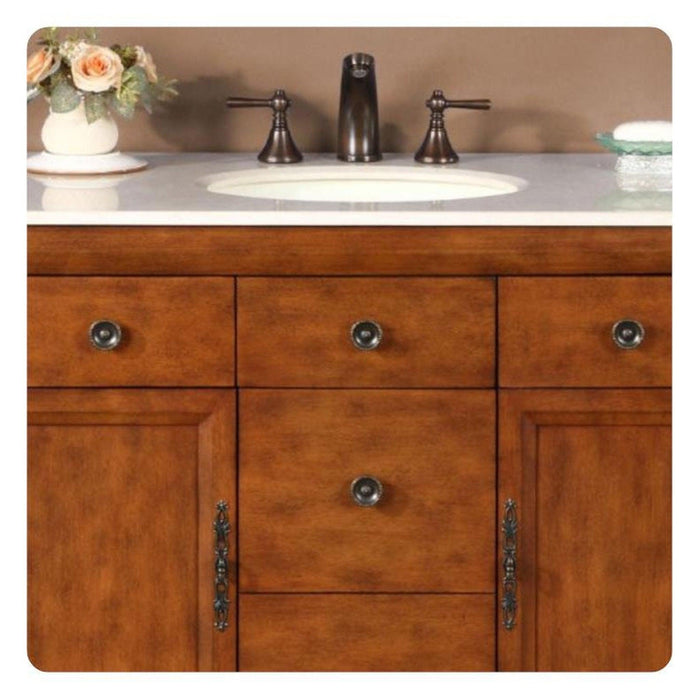 Wooden bathroom vanity with bronze faucet, white sink, and soft peach roses in a vase