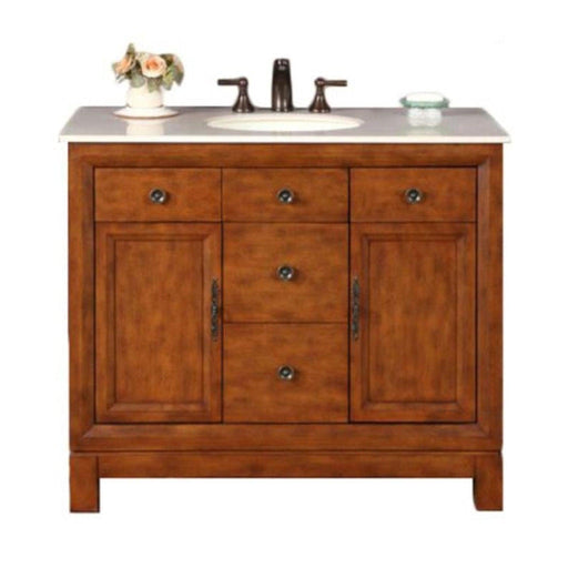 Wooden bathroom vanity with white marble top, bronze faucet, three drawers, two cabinets, and a small vase of roses.