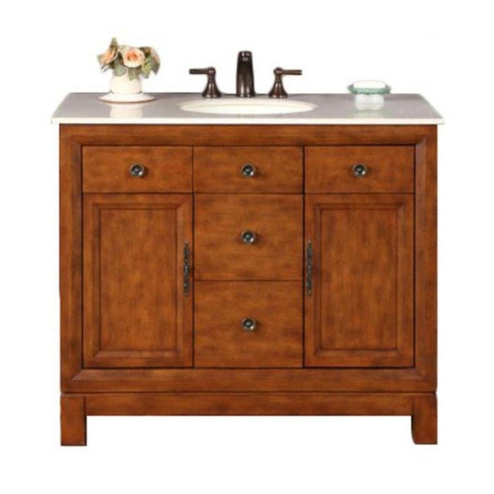 Wooden bathroom vanity with white marble top, bronze faucet, three drawers, two cabinets, and a small vase of roses.