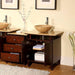 Dark wood bathroom vanity with two stone vessel sinks, open cabinet, and decorative vase with delicate flowers