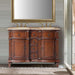 Elegant wooden double vanity with rich brown finish, two sinks, brass fixtures, and ornate carved details, set against shiplap wall.